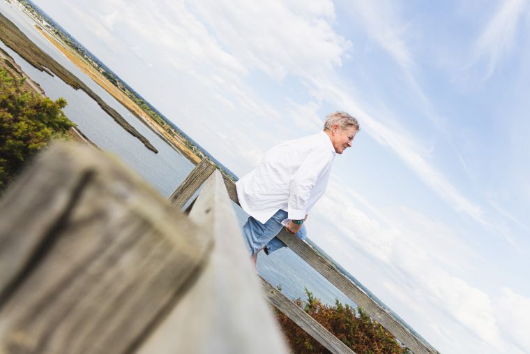 How To Ditch Your Guilt And Move On Blog Image | Jules Whale Life Coach sitting on a fence with the sea and coastline behind her in Dorset