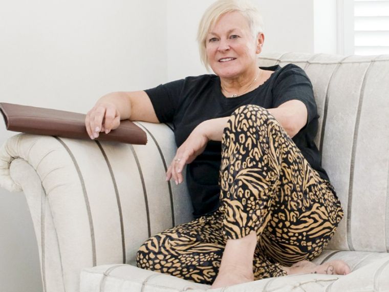 Portrait image of jules whale sitting on her sofa with a brown folder.